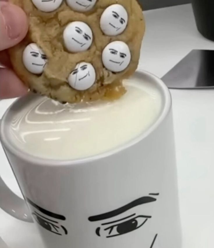 man face cookie dipped in man face mug of milk